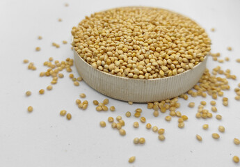 Millet seeds in a bowl on a white background, subject photography.