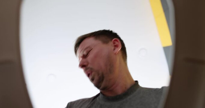 A man appears completely shocked as he looks down into a toilet bowl from an overhead viewpoint above it