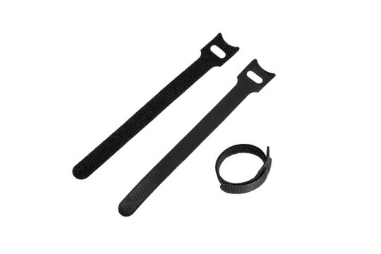 Three black hook-and-loop cable ties, two flat and one coiled, used for organizing and securing cables, wires, or items, isolated on a white back