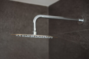 Pristine water droplets streaming from contemporary shower head, revealing clean bathroom design...