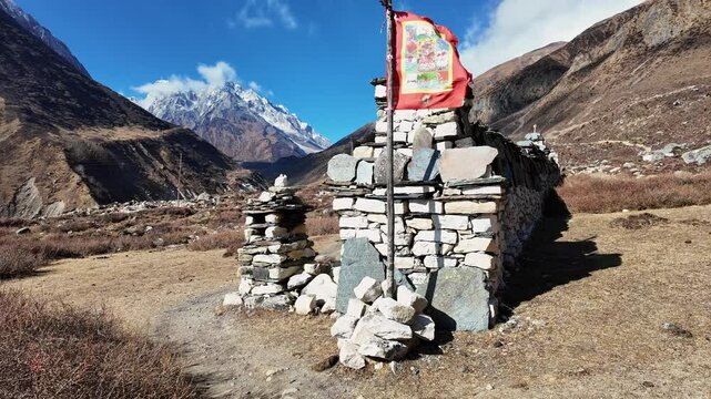 Larke Pass, Nepal: Hiker walks along the Manaslu circuit between Samdo and the Larke pass by Tibetan Buddhist flag and mani wall at 5106m in the Himalaya in Nepal