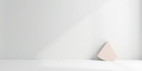 A Minimalist Scene Featuring a Pale Pink Geometric Shape Against a Bright White Wall with Soft Natural Light