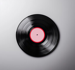 Fototapeta premium Black vinyl record with red label, isolated on light background, showcasing its classic design and texture. Perfect for music lovers and collectors
