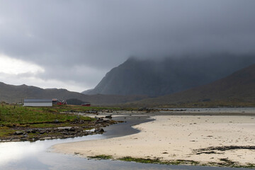 Panoramic view on the mountain range seen from Morpheus Beach on on the Lofoten island chain archipelago in Norway near Napp and Flakstad with white heavy cloud cover hanging over the mountains