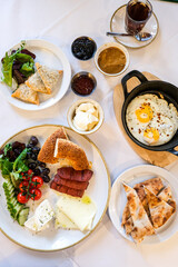 Turkish or Mediterranean style breakfast. Turkish breakfast. Variety of fresh vegetables, olives, cheeses, jams and spreads on a small plates on a white tablecloth covered table. Traditional turkish 