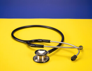 Medical stethoscope lying on a vibrant yellow background with contrasting blue accents.