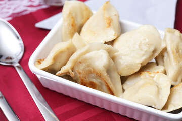 Traditional Polish dumplings on a festive Christmas table with a red tablecloth. Classic Christmas Eve dish with mushroom and cabbage filling. Iconic Eastern European holiday food Pierogi background.