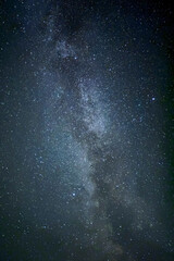 The vast night sky, adorned with countless twinkling stars, stretches endlessly above, casting a serene glow over the quiet landscape below
