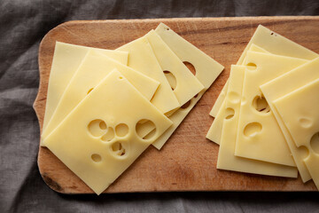 Slices of Maasdam cheese on a wooden board, top view. Close-up.
