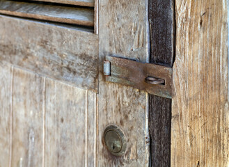 Old rusty metal security Padlock Hasp and keyhole on brown old aged wooden door without lock.