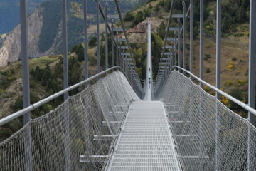 The Andorra Tibetan Bridge, known as Pont Tibetà Canillo, stretches high above a deep valley, offering stunning views of the surrounding mountains and landscape.

