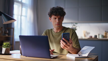 Disappointed freelancer receiving message on cellphone working home closeup