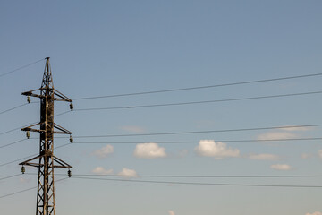 Electricity pylons against the blue sky with white clouds.