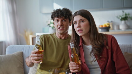 Sport fans feeling despair for team lose watching match at home couch closeup