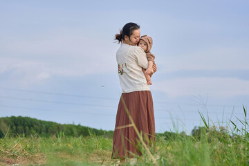 there is a woman holding a baby in a field of tall grass