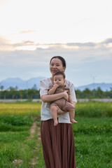 there is a woman holding a baby in a field of grass