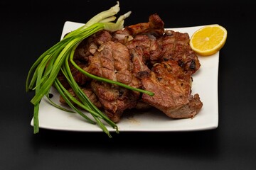 Fresh fried pork kebab with lemon and onion on a white plate. Barbecue meat.