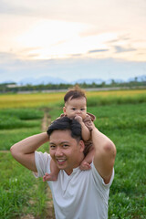 there is a man holding a child on his shoulders in a field