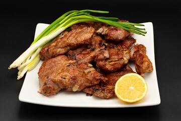 Fresh fried pork kebab with lemon and onion on a white plate. Barbecue meat.