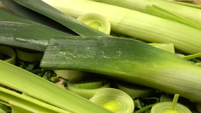Whole and cut, peeled and unpeeled leek and celery lie on a chopped dill and parsley