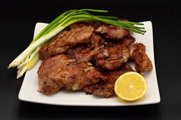 Fresh fried pork kebab with lemon and onion on a white plate. Barbecue meat.