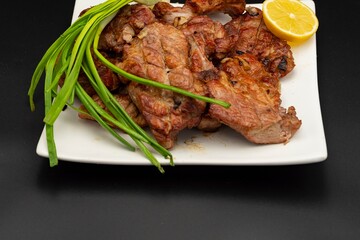 Fresh fried pork kebab with lemon and onion on a white plate. Barbecue meat.