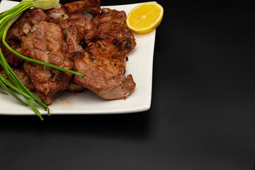 Fresh fried pork kebab with lemon and onion on a white plate. Barbecue meat.