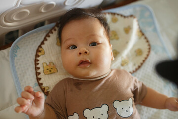 a baby in a brown shirt sitting on a bed