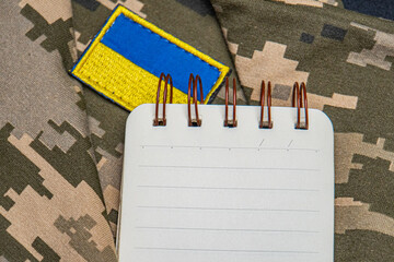 Military notepad. Ukraine flag. Military themed overhead flat lay of personal items laid out on a...
