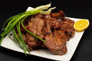 Fresh fried pork kebab with lemon and onion on a white plate. Barbecue meat.