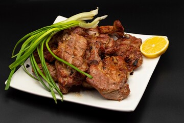 Fresh fried pork kebab with lemon and onion on a white plate. Barbecue meat.