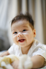 a baby sitting on a bed with a banana in it's mouth