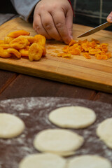Jewish woman makes a filling of dried fruits and poppy seeds for baking on a wooden table