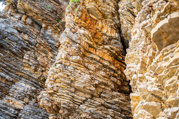 Layered rock texture in Budva, Montenegro. Sedimentary rocks with rugged surface of gray and brown....