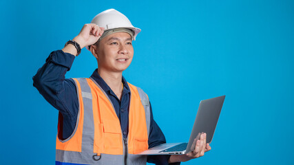 Confident young engineer wearing orange and a safety helmet stands holding a laptop, phone with various emotions.