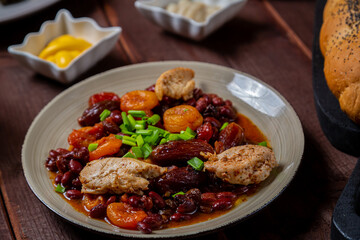 beans stewed with meat and dried fruits and sauce and hummus in a plate