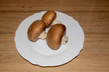 Three champignon mushrooms on a white plate. Ingredient for different dishes. Food three champignons