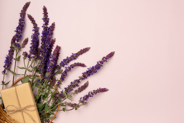 Mint flowers in basket with gift box on pink background. Flat lay, top view.