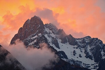  Sunset Over Snow-Capped Mountain Peaks with Orange Sky and Clouds