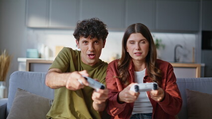 Gamers spouses playing video games using controllers sitting cozy couch together © stockbusters