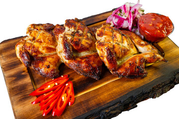Grilled chicken served on a wooden platter with vibrant sides at a dining table