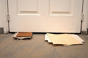  The image depicts a white door with peeling paint situated on a worn concrete floor