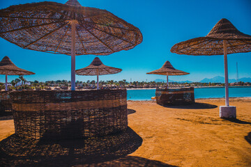 Umbrellas and sun loungers against the background of blue sky and red sea. Landscape of Egypt on vacation