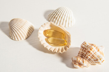 Yellow vitamins in seashells on white background. Fish oil