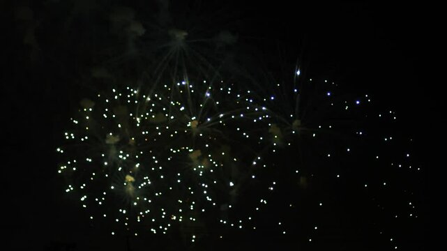 silver gold green sparks scattering fireworks on the black night sky. General plan