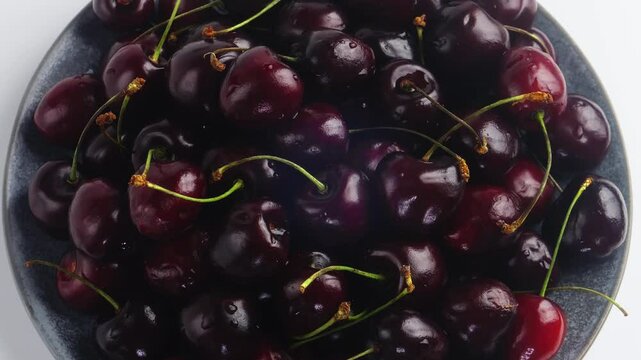 Scattering of ripe dark red cherries rotating in a circle. Medium plan
