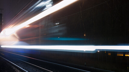 beams of lights from a passing train on a railway at night