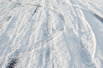 car tire marks on snowy road.