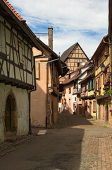 Beautiful view of ancient narrow cobblestone street with colorful houses in Eguisheim, France. Traditional architecture in Alsace in northeastern France. Travel and tourism concept. Sunny spring day