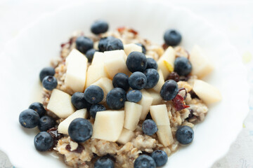 Healthy oatmeal breakfast bowl topped with fresh blueberries and diced pears. A delicious and nutritious start to the day!